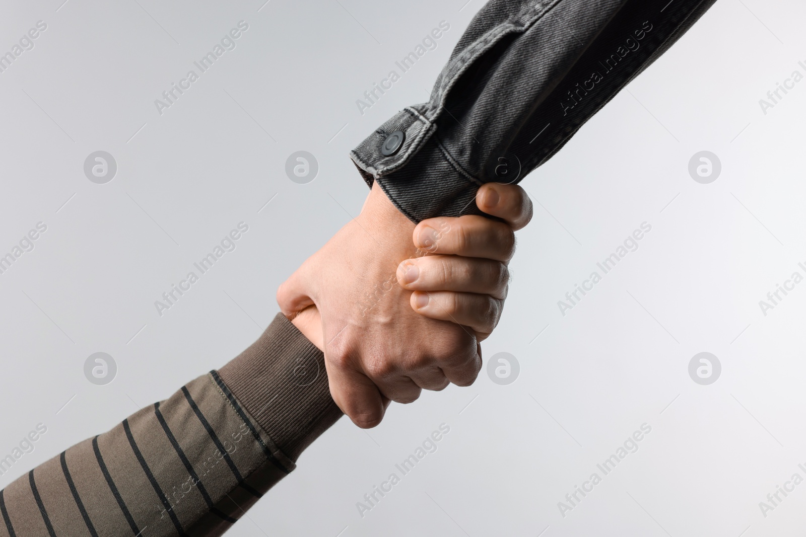 Photo of Help and support. People holding hands on light grey background, closeup