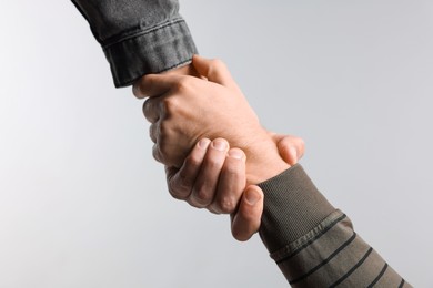 Photo of Help and support. People holding hands on light grey background, closeup