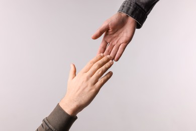 Photo of Man reaching for helping hand on light grey background, closeup