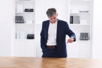 Photo of Man pointing at something on desk in office