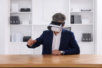 Photo of Man using virtual reality headset at desk in office