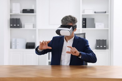 Photo of Man using virtual reality headset at desk in office