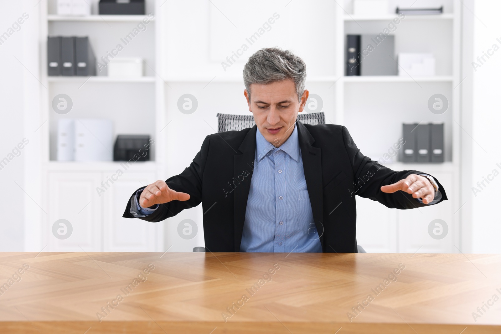 Photo of Man showing something at desk in office