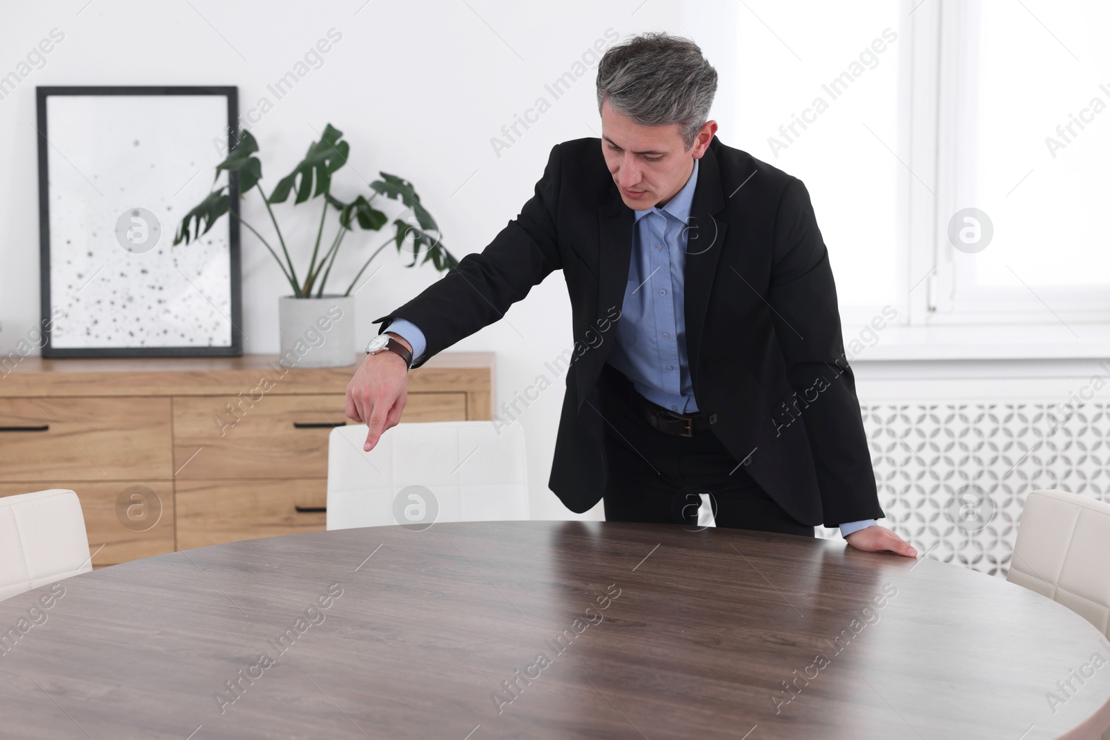 Photo of Man pointing at something on desk in office