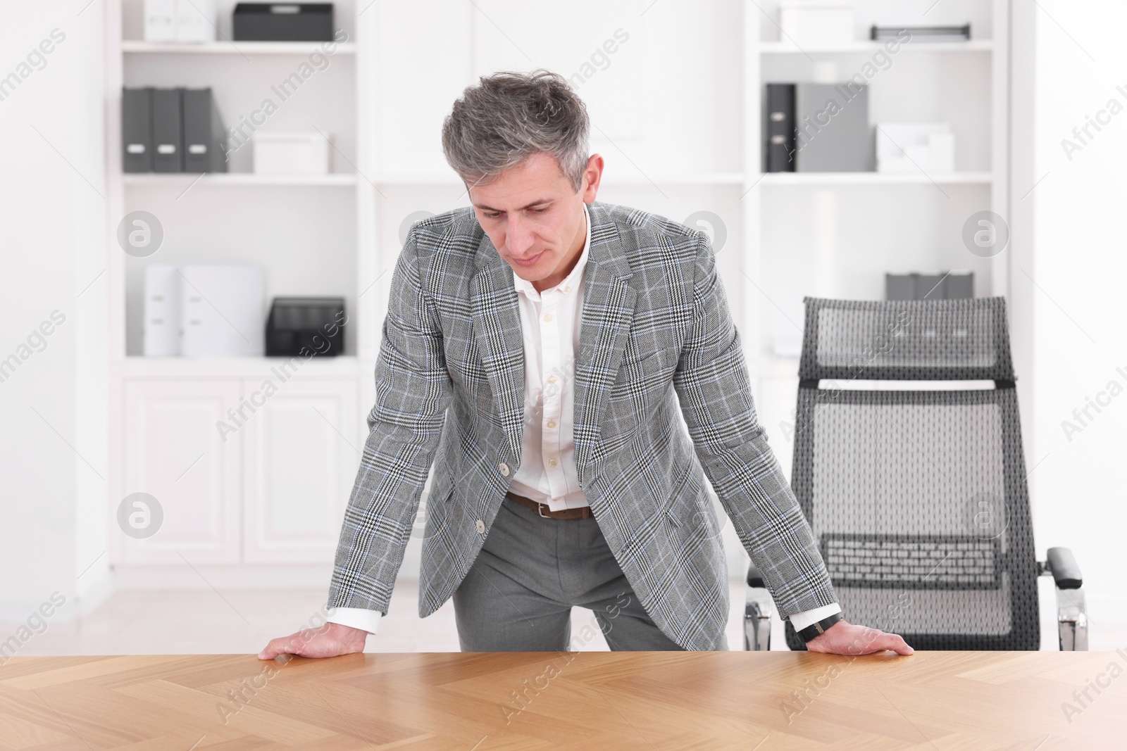 Photo of Man looking at something on desk in office