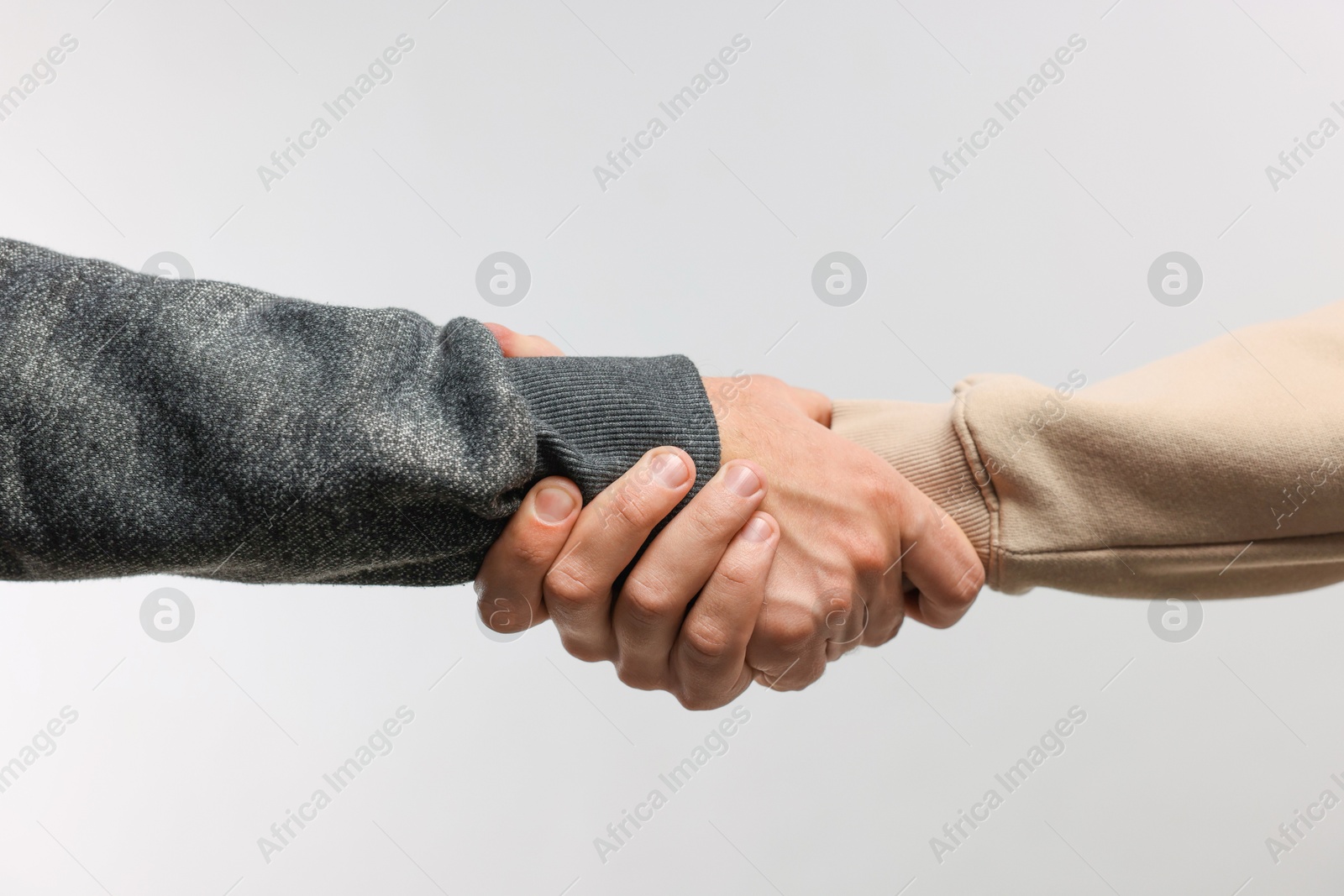 Photo of Help and support. People holding hands on light grey background, closeup