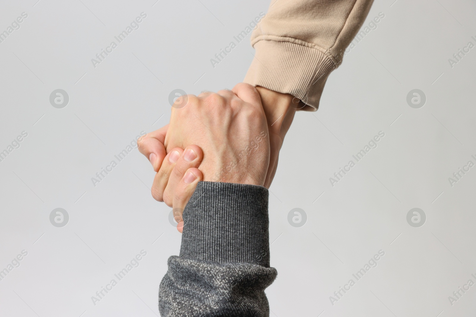 Photo of Help and support. People holding hands on light grey background, closeup