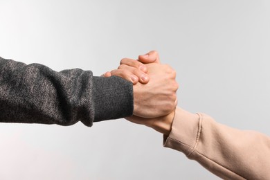 Photo of Help and support. People holding hands on light grey background, closeup