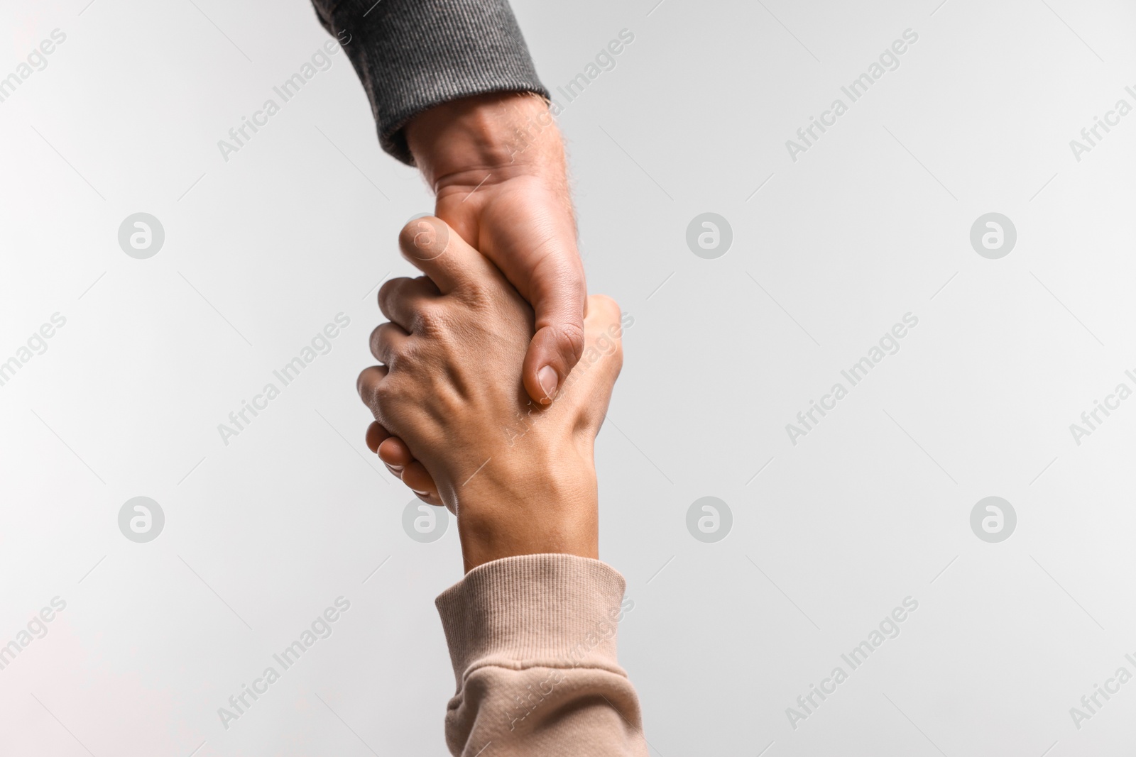 Photo of Help and support. People holding hands on light grey background, closeup