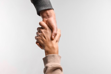 Photo of Help and support. People holding hands on light grey background, closeup