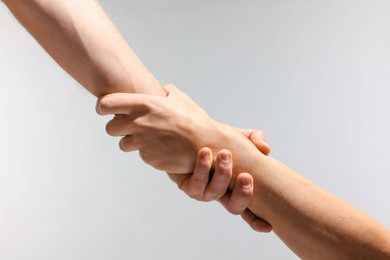 Photo of Help and support. People holding hands on light grey background, closeup