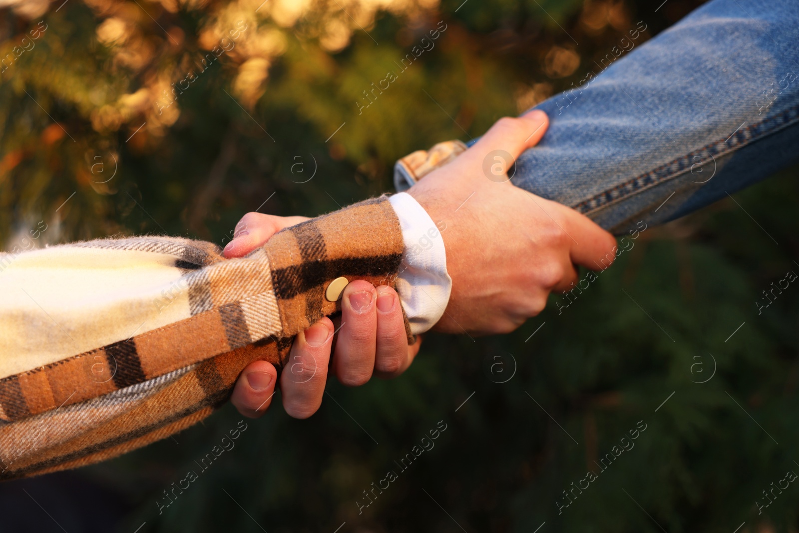 Photo of Help and support. People holding hands outdoors, closeup