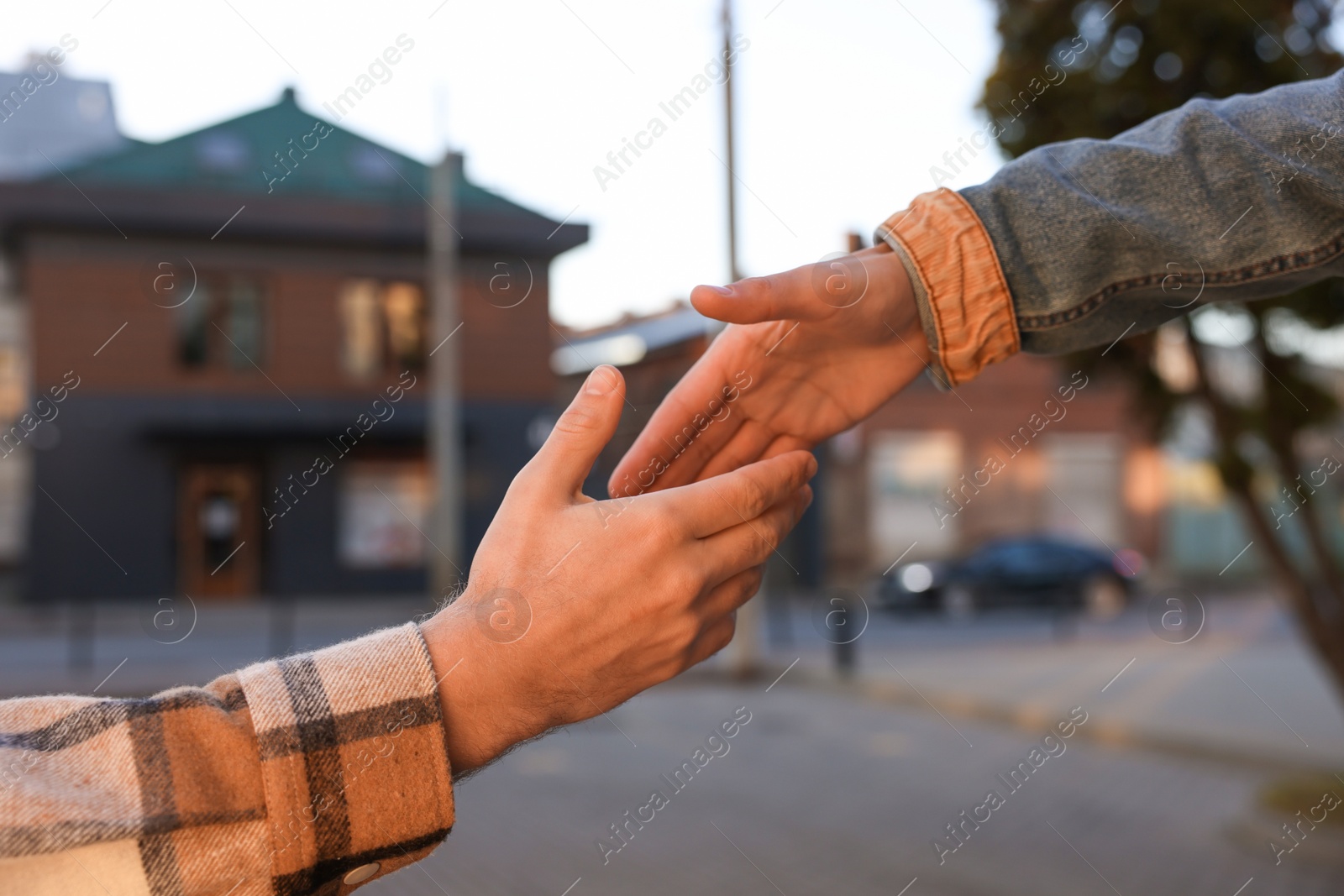 Photo of Man offering helping hand to his friend on city street, closeup