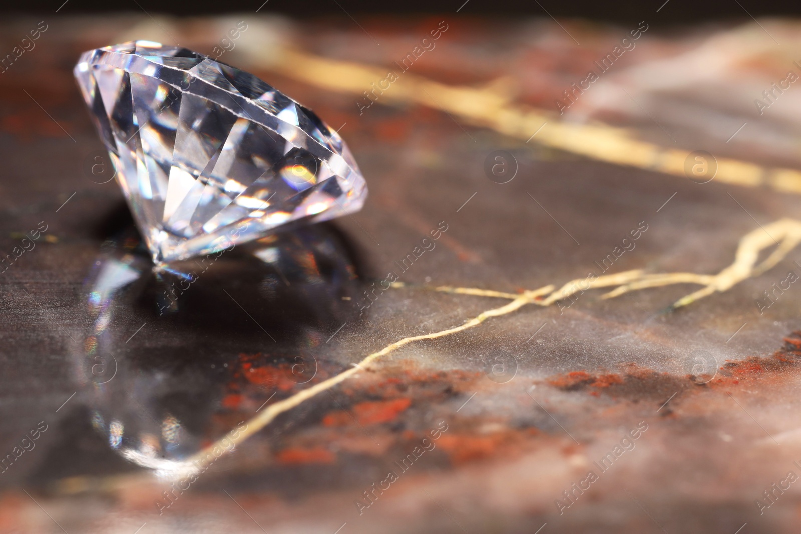 Photo of Beautiful shiny gemstone on brown marble surface, closeup. Space for text