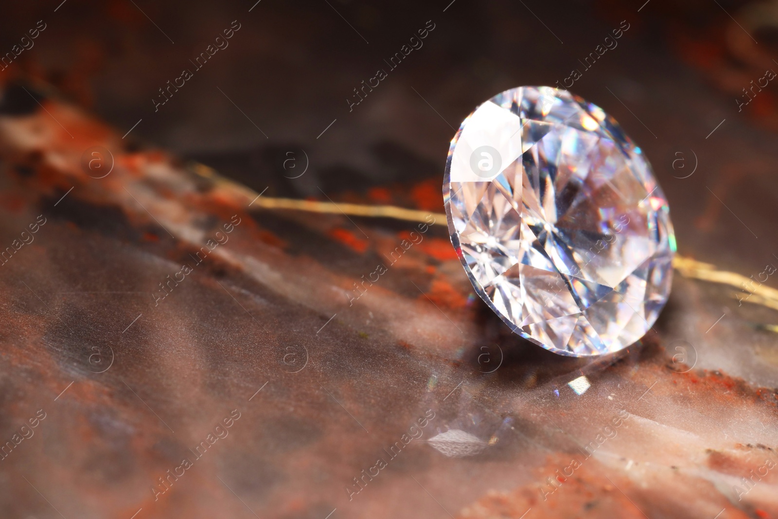 Photo of Beautiful shiny gemstone on brown marble surface, closeup. Space for text