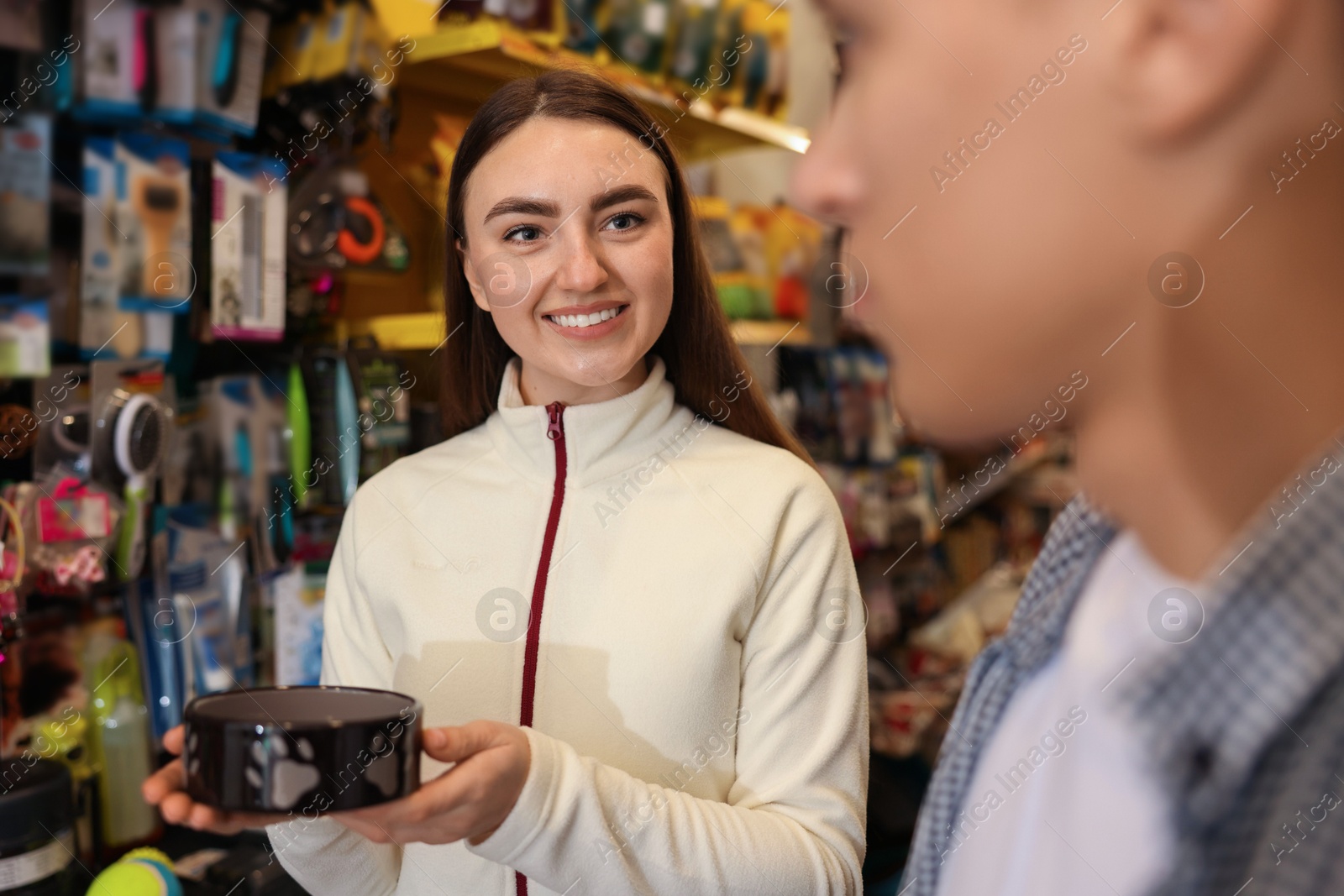 Photo of Young couple choosing feeding bowl in pet shop, selective focus