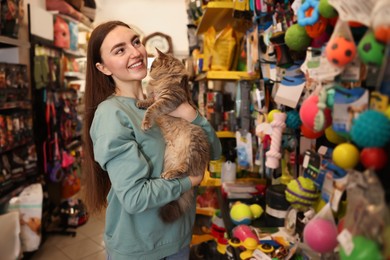 Photo of Happy woman with her cute cat looking at toys in pet shop