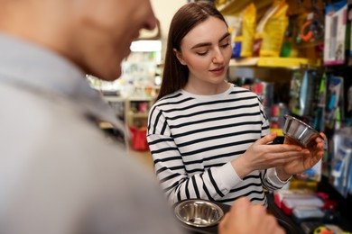 Man and woman choosing bowl in pet shop, selective focus