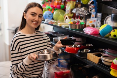 Photo of Woman choosing feeding bowl in pet shop