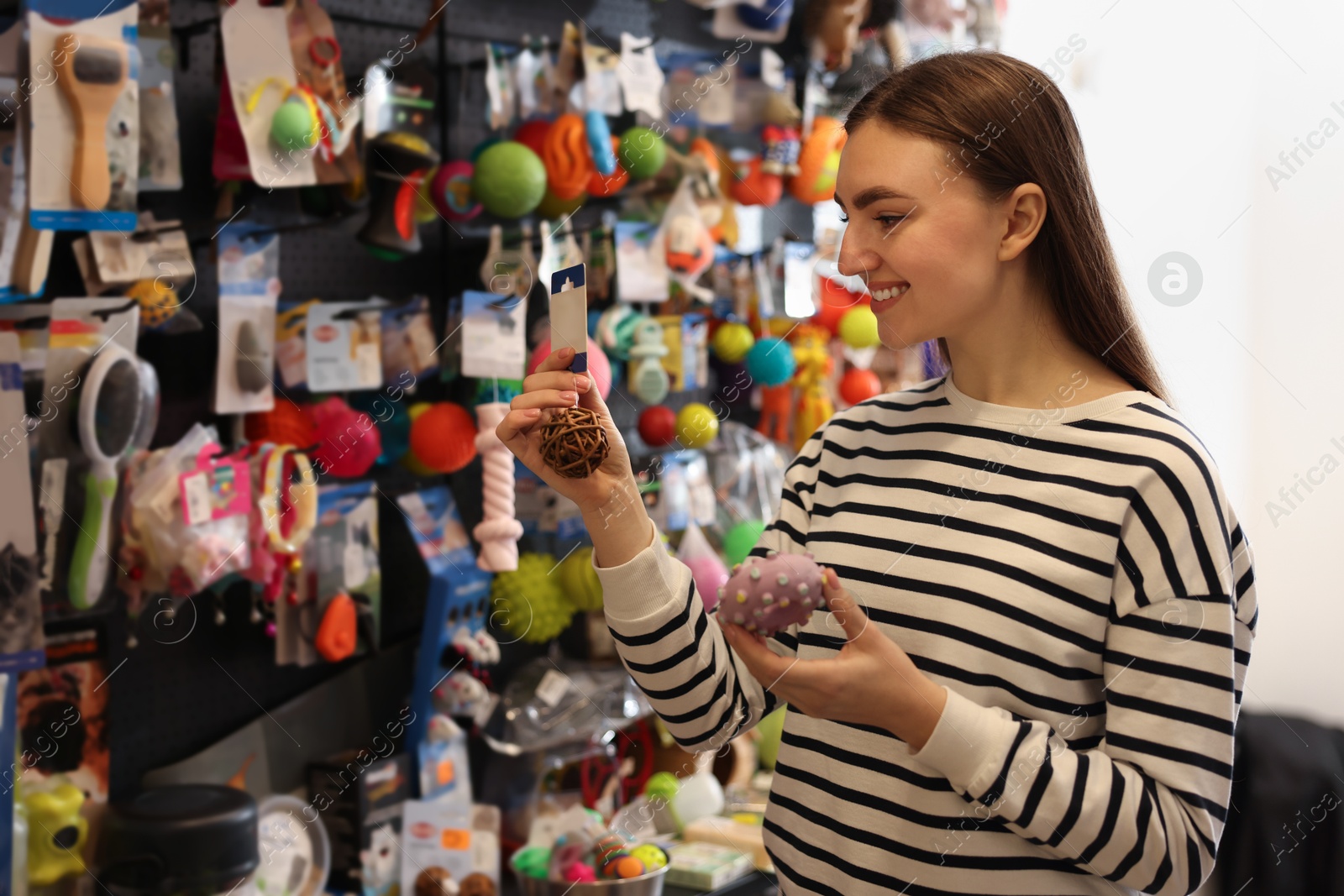 Photo of Young woman choosing toys in pet shop