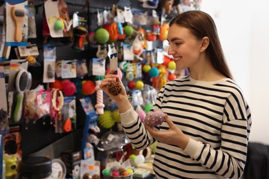 Photo of Young woman choosing toys in pet shop