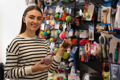 Photo of Young woman choosing toys in pet shop