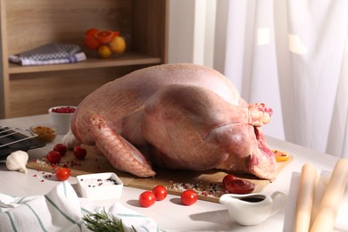 Photo of Whole raw turkey and ingredients on white wooden table