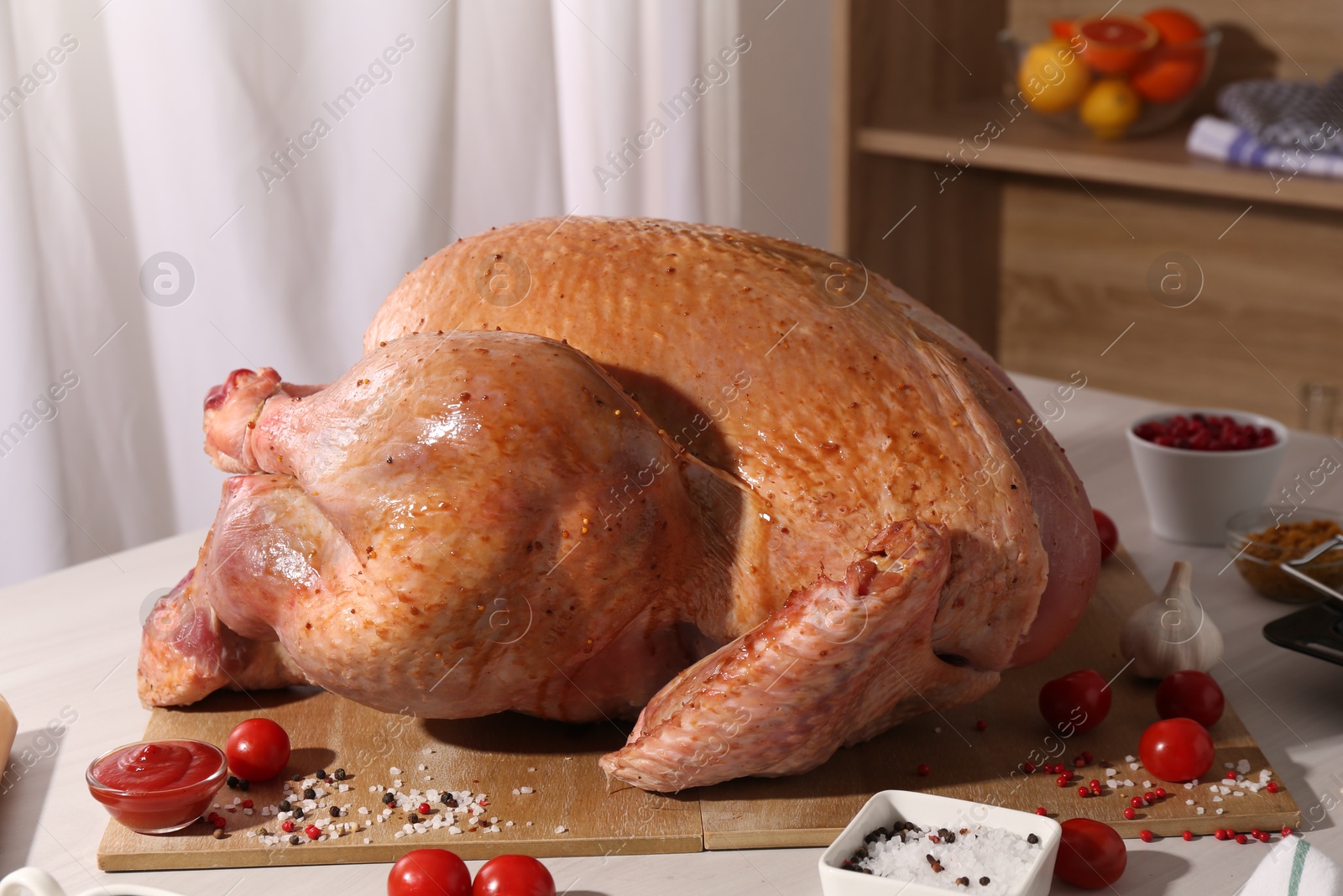 Photo of Whole raw turkey with marinade and ingredients on white wooden table