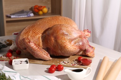 Photo of Whole raw turkey with marinade and ingredients on white wooden table