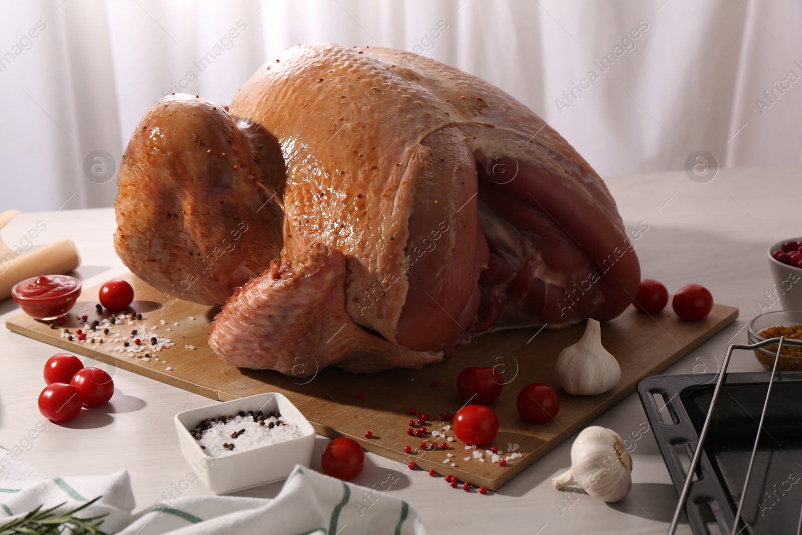 Photo of Whole raw turkey with marinade and ingredients on white wooden table