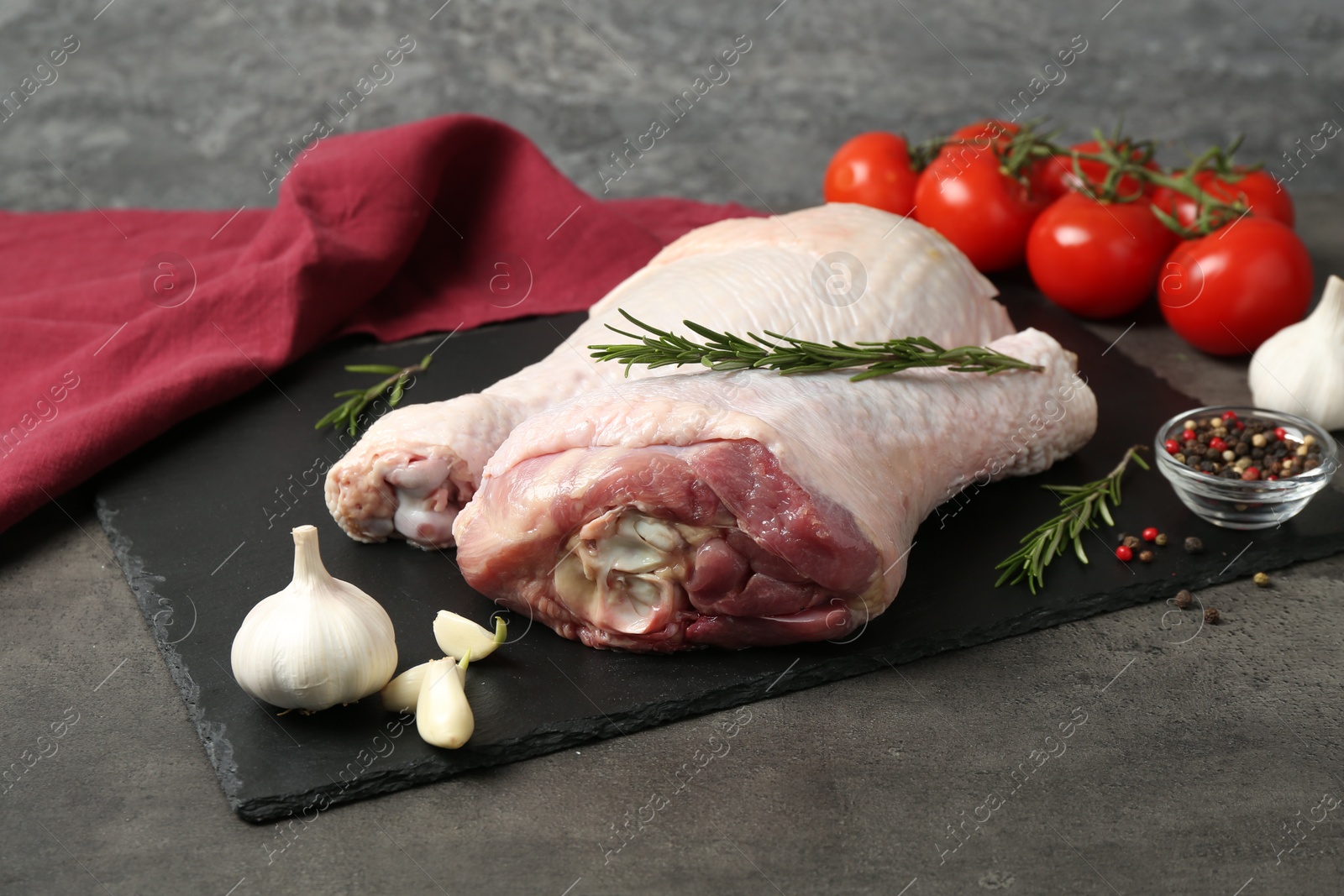 Photo of Raw turkey drumsticks and ingredients on grey table, closeup