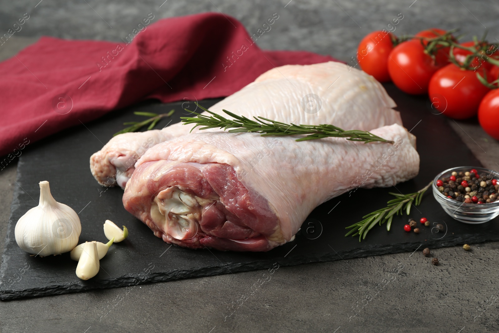 Photo of Raw turkey drumsticks and ingredients on grey table, closeup