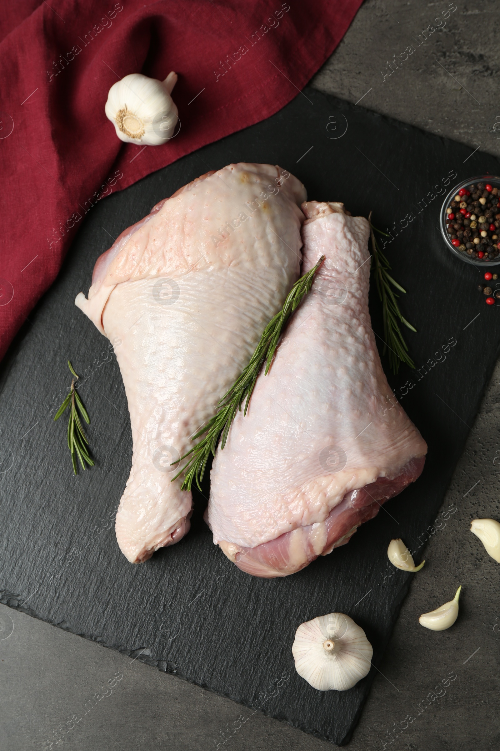 Photo of Raw turkey drumsticks and ingredients on grey table, flat lay