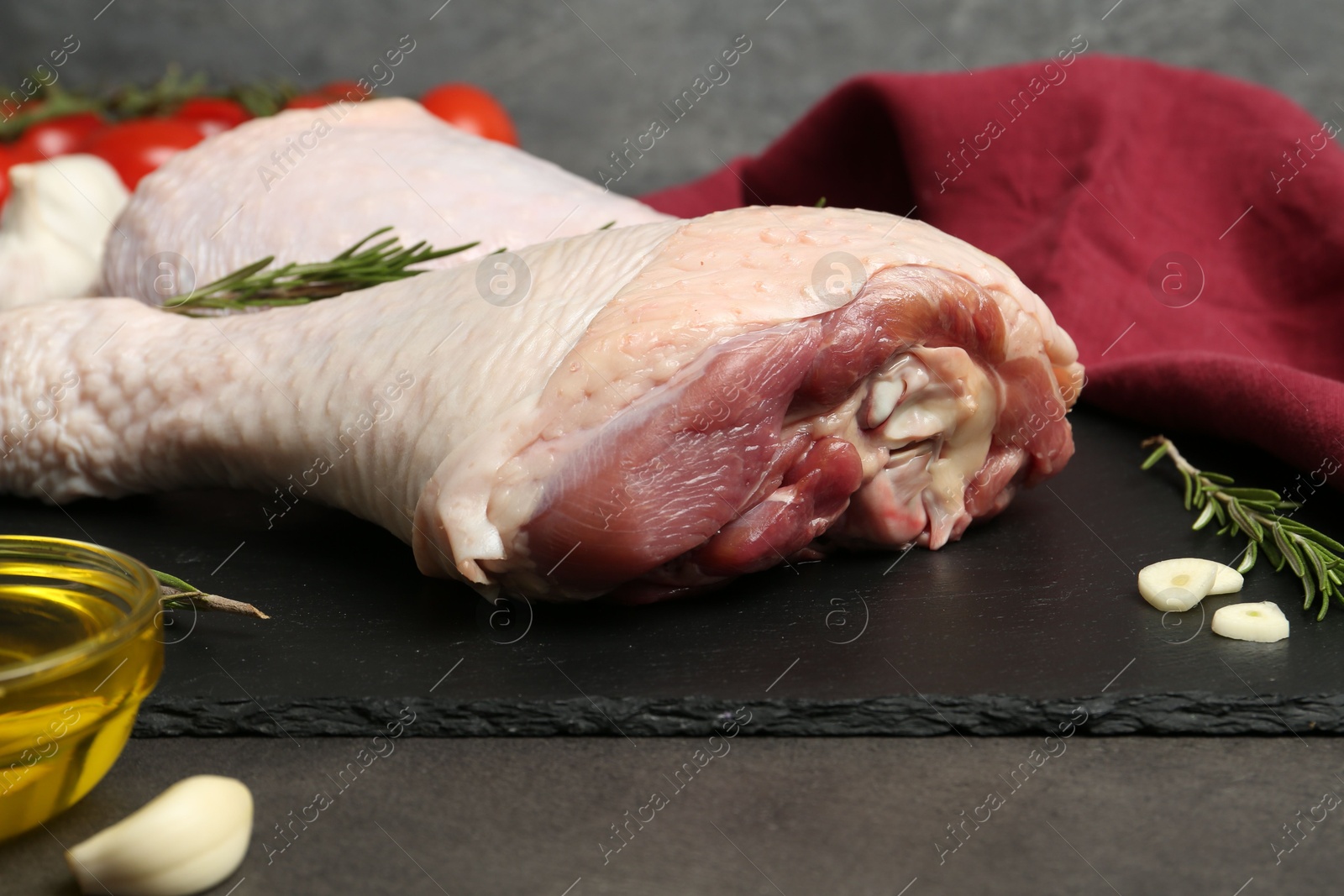 Photo of Raw turkey drumsticks and ingredients on grey table, closeup