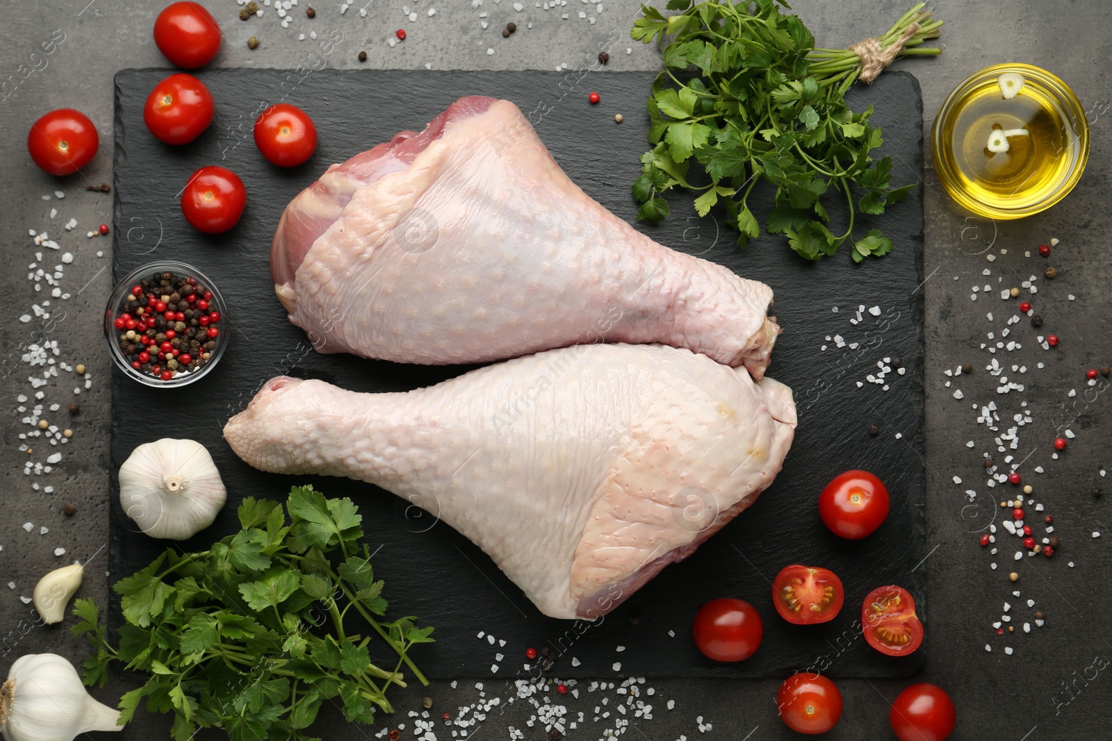 Photo of Raw turkey drumsticks and ingredients on grey table, flat lay