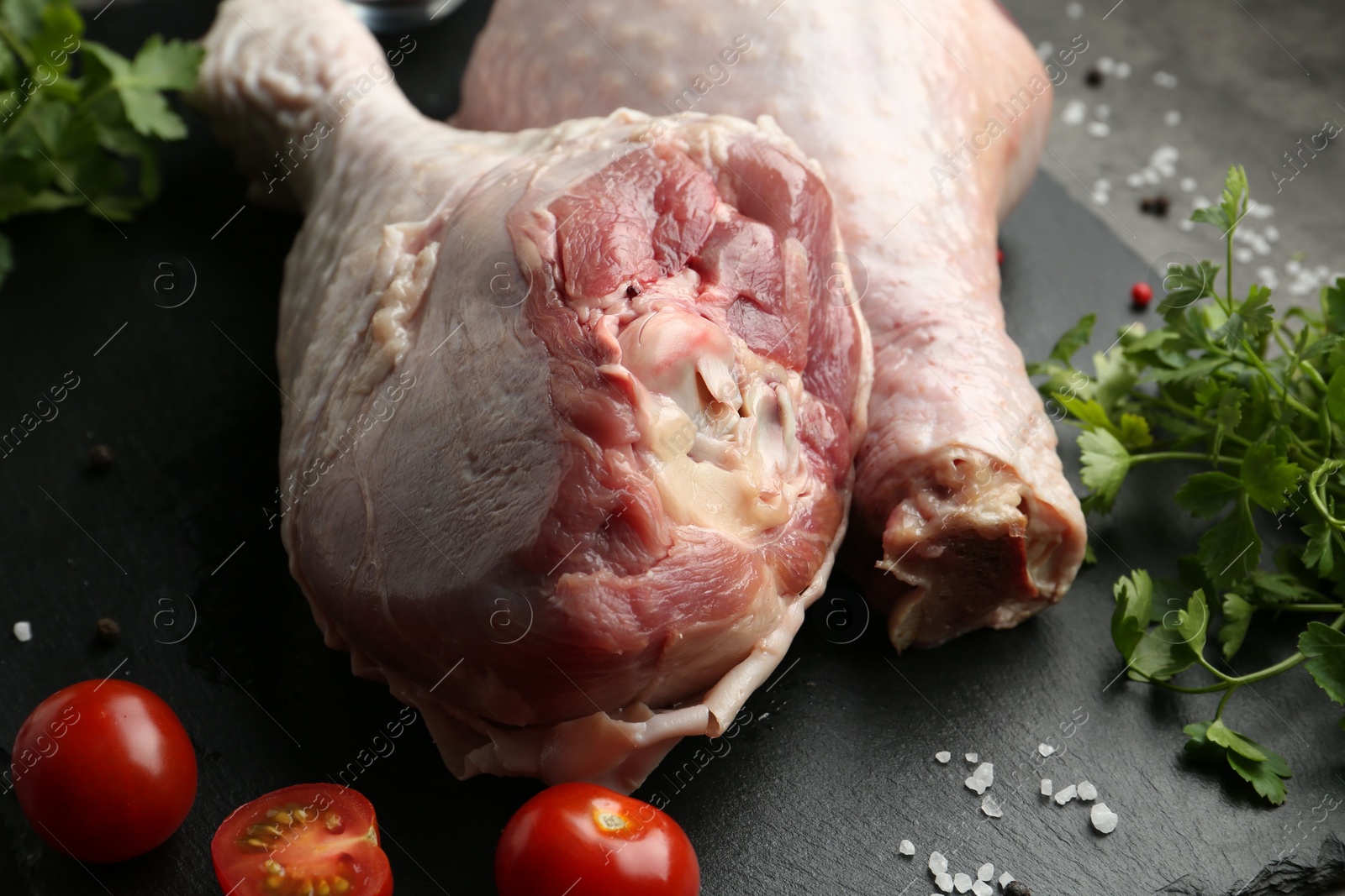 Photo of Raw turkey drumsticks and ingredients on grey table, closeup