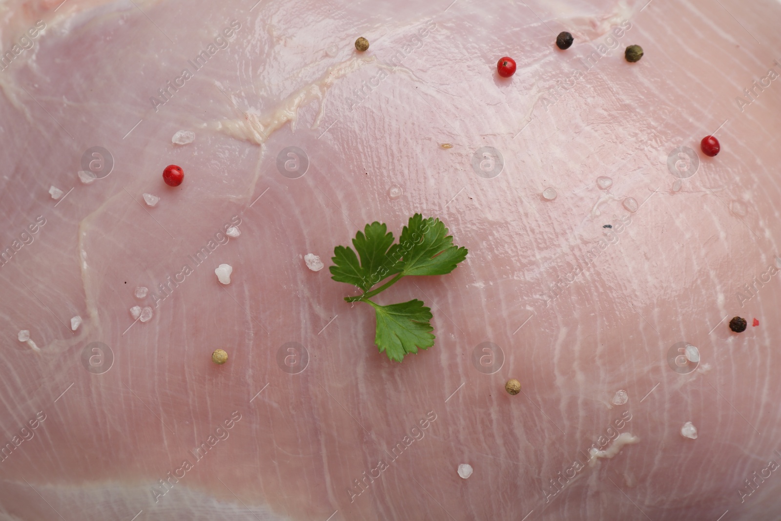 Photo of Raw turkey breast, parsley and peppercorns as background, top view