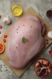 Photo of Raw turkey breast and ingredients for marinade on grey textured table, flat lay