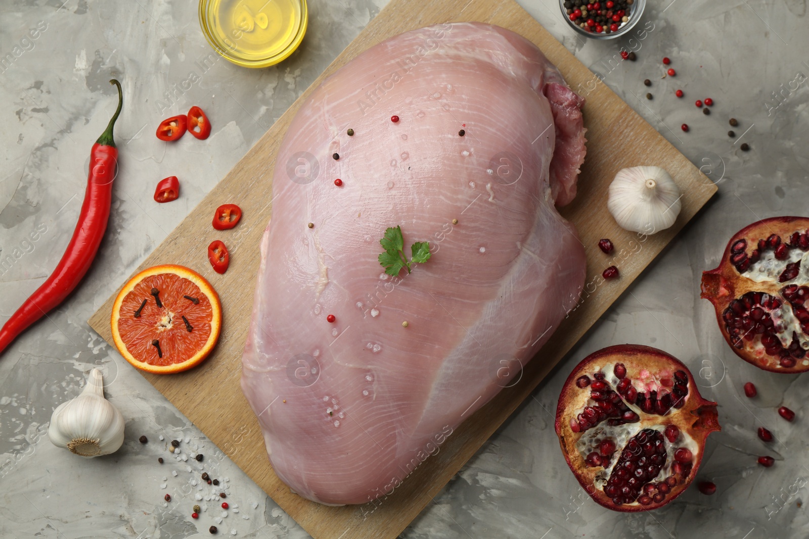 Photo of Raw turkey breast and ingredients for marinade on grey textured table, flat lay