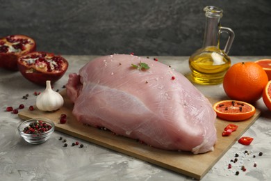 Photo of Raw turkey breast and ingredients for marinade on grey textured table