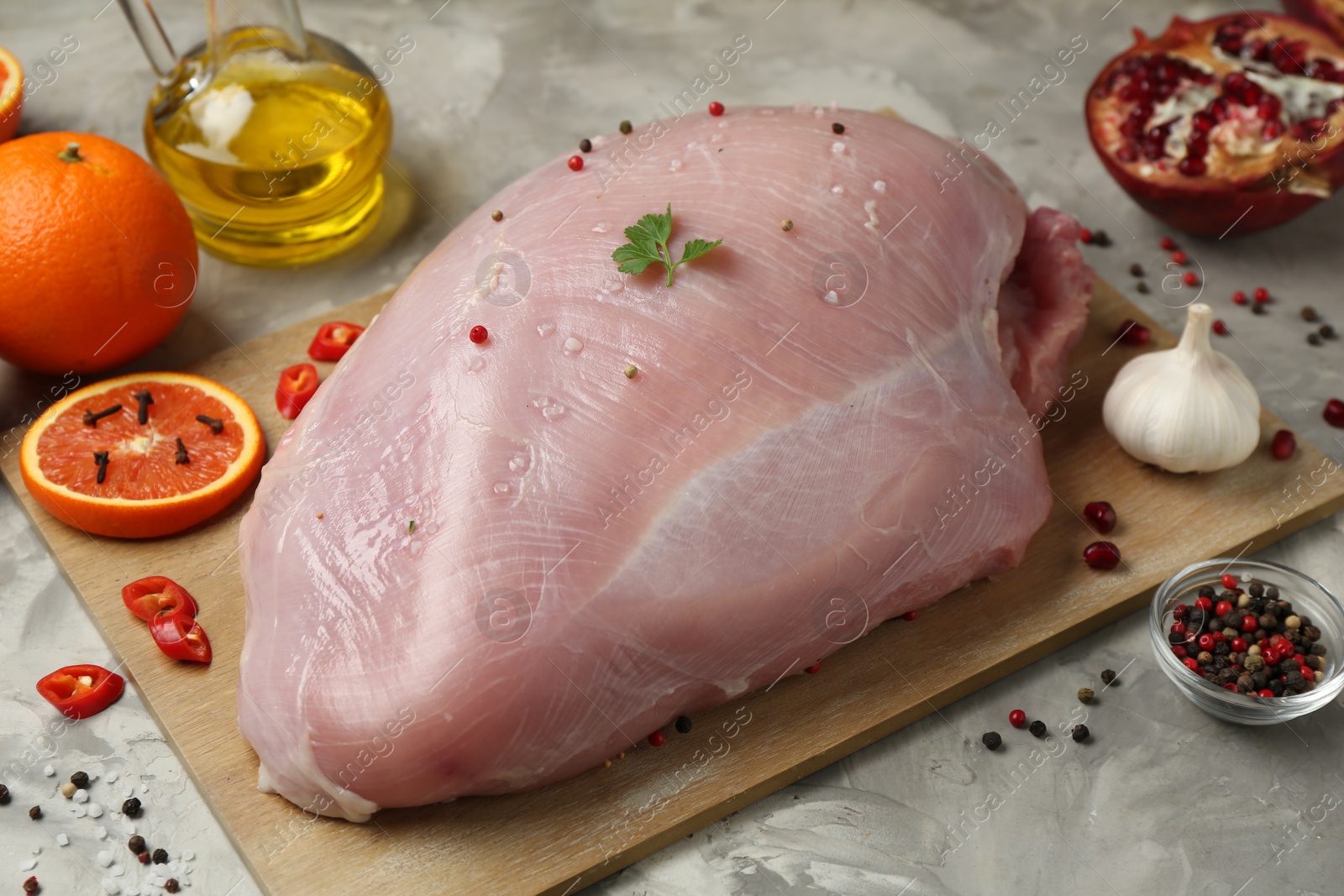 Photo of Raw turkey breast and ingredients for marinade on grey textured table, closeup