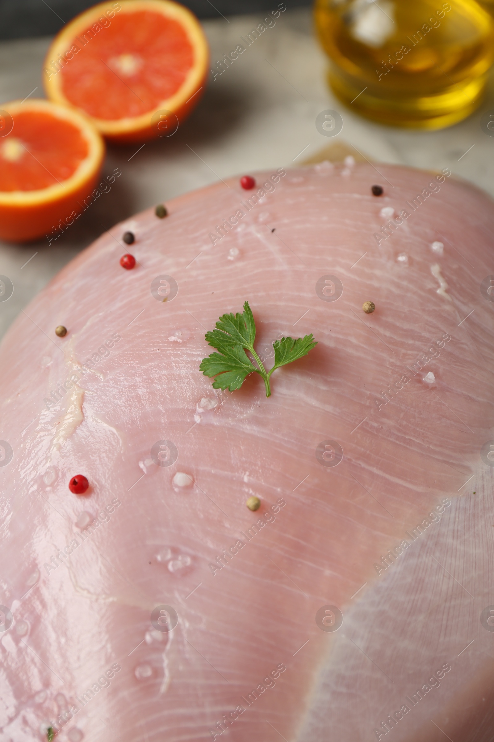 Photo of Raw turkey breast with peppercorns on table, closeup