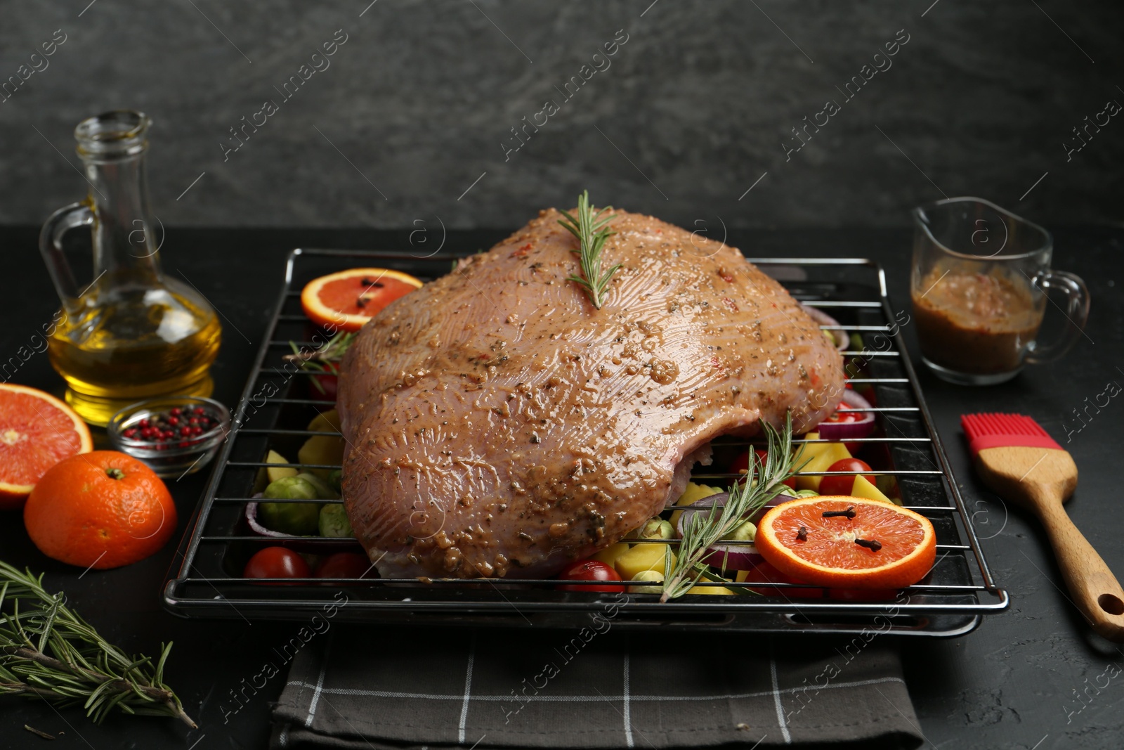 Photo of Raw turkey breast with marinade and ingredients on black table