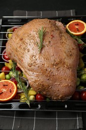 Photo of Raw turkey breast with marinade and ingredients on black table, closeup