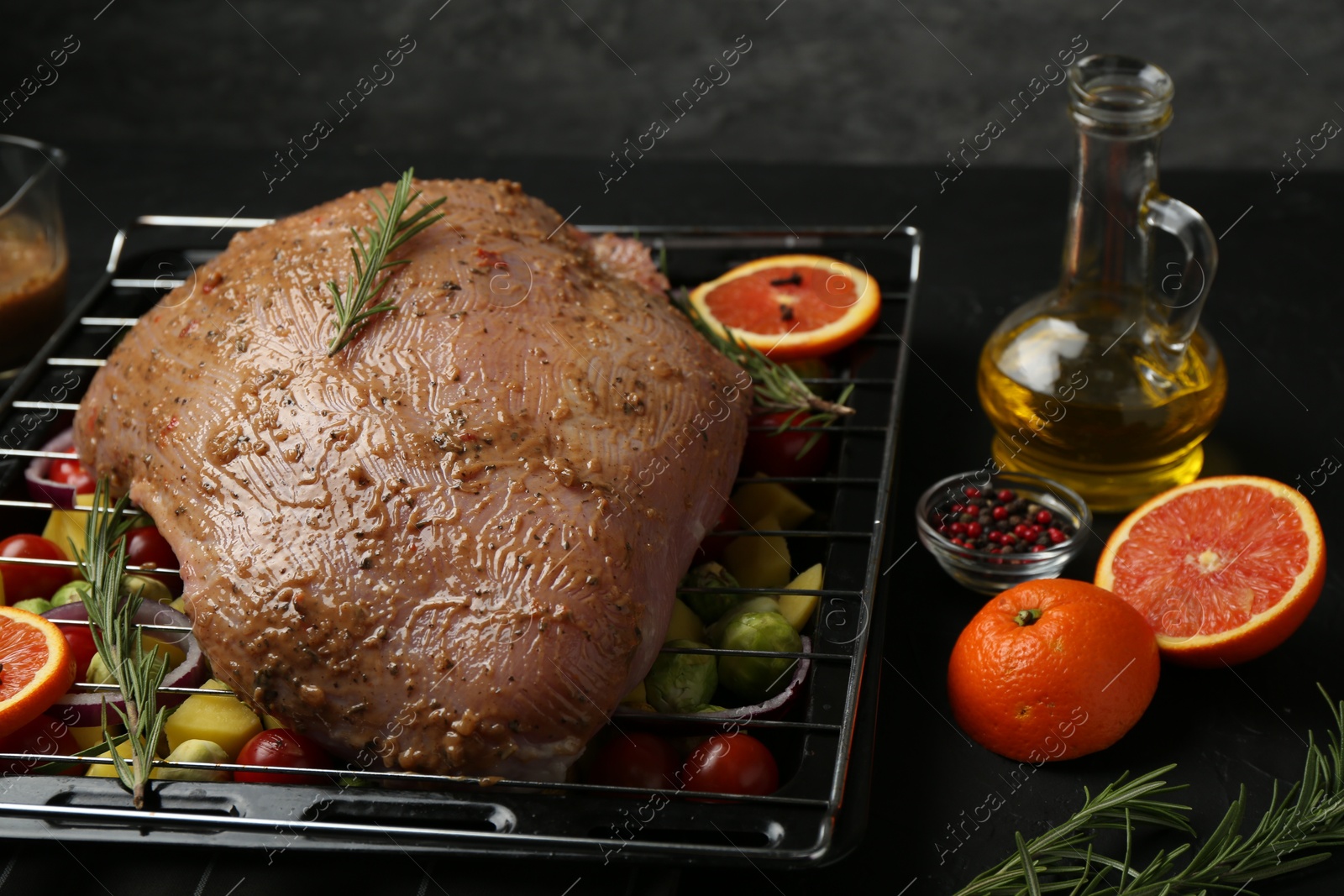 Photo of Raw turkey breast with marinade and ingredients on black table