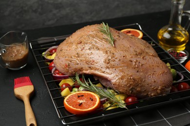 Photo of Raw turkey breast with marinade and ingredients on black table