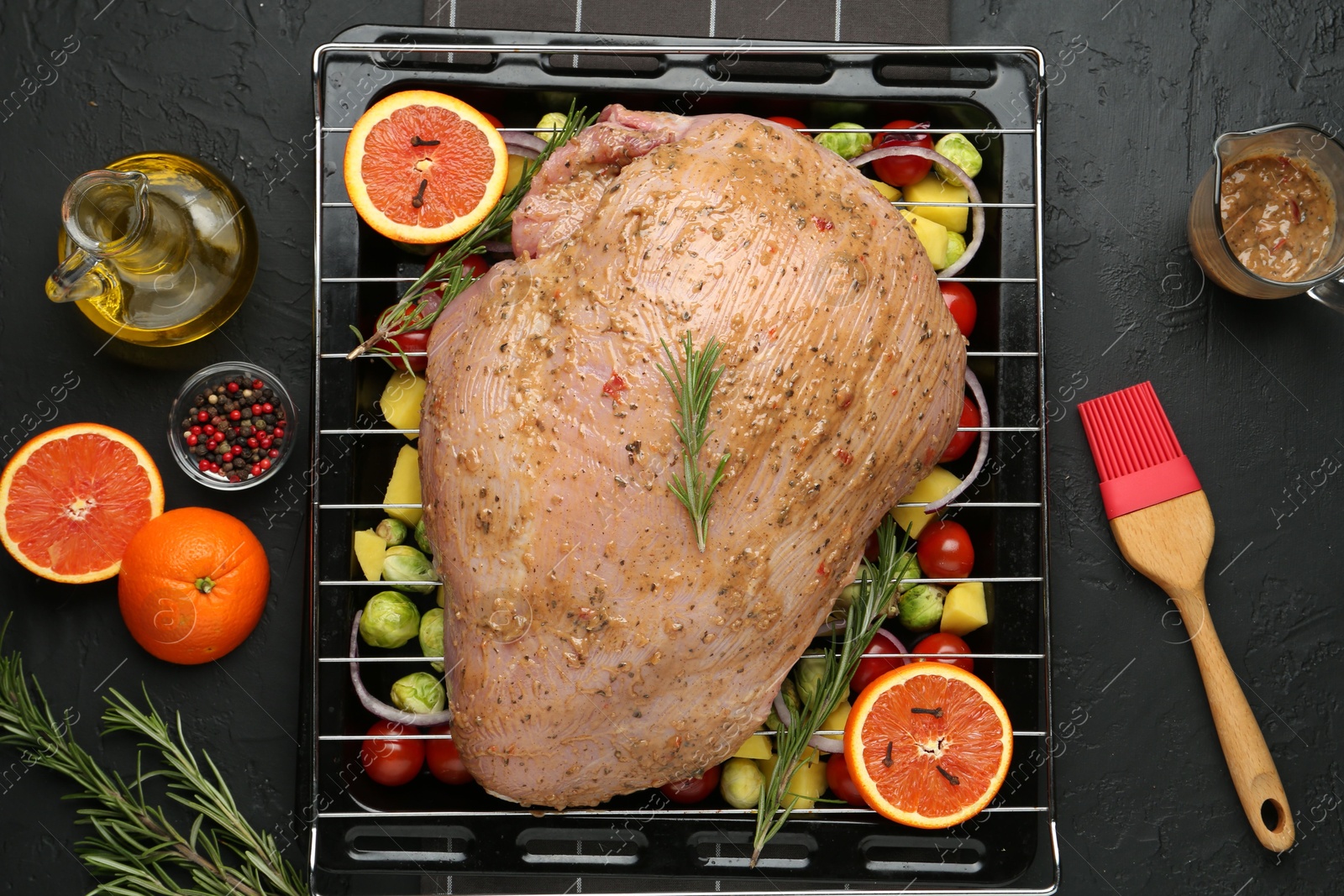 Photo of Raw turkey breast with marinade and ingredients on black table, flat lay