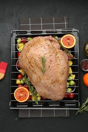 Photo of Raw turkey breast with marinade and ingredients on black table, flat lay