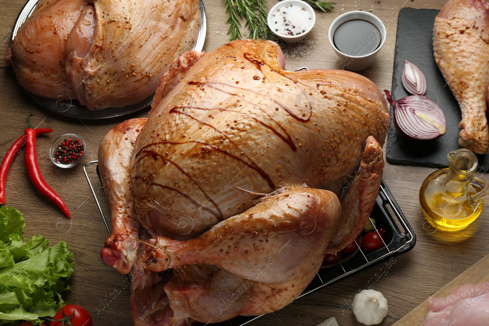 Photo of Raw marinated turkey meat and products on wooden table