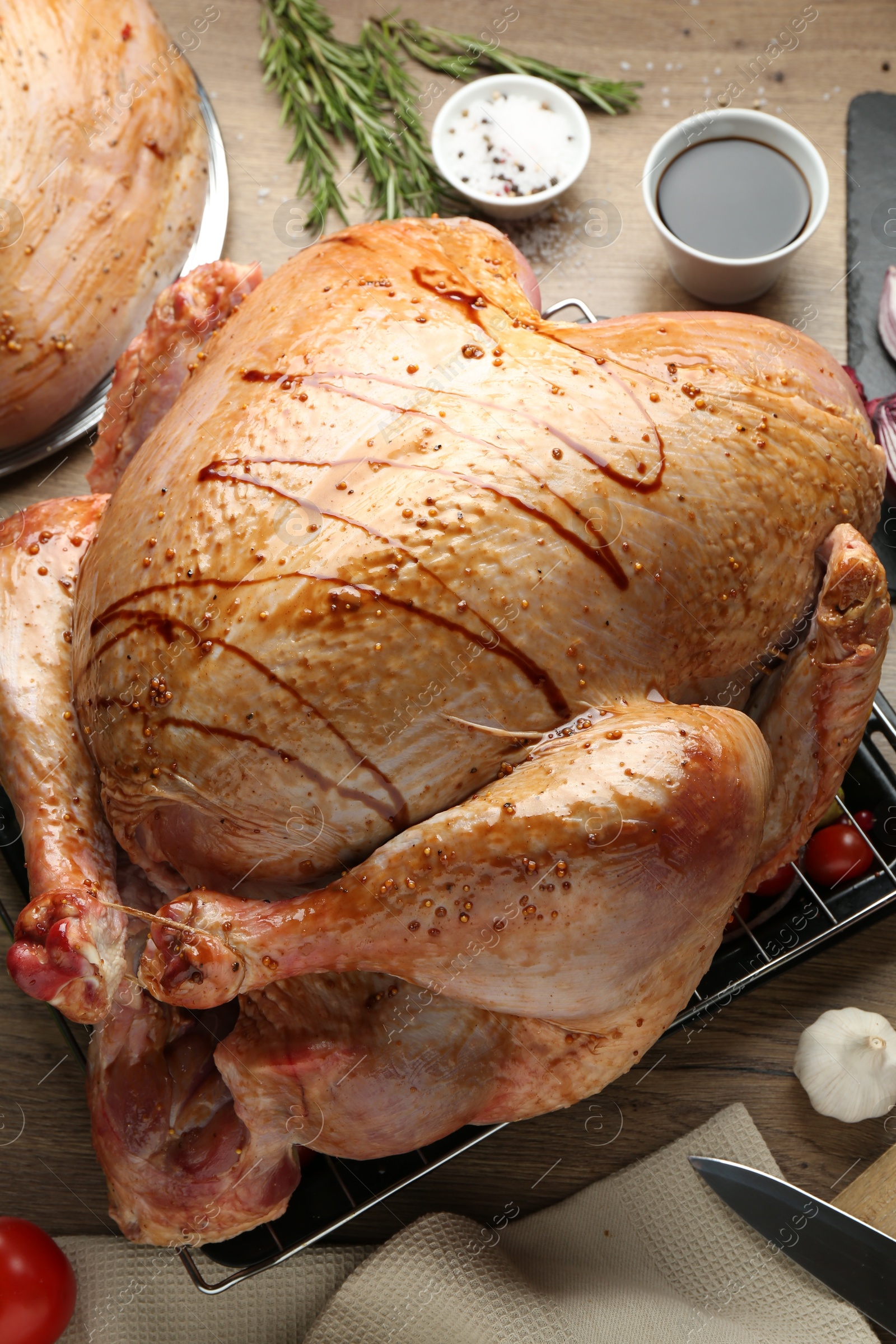 Photo of Whole raw marinated turkey and products on wooden table